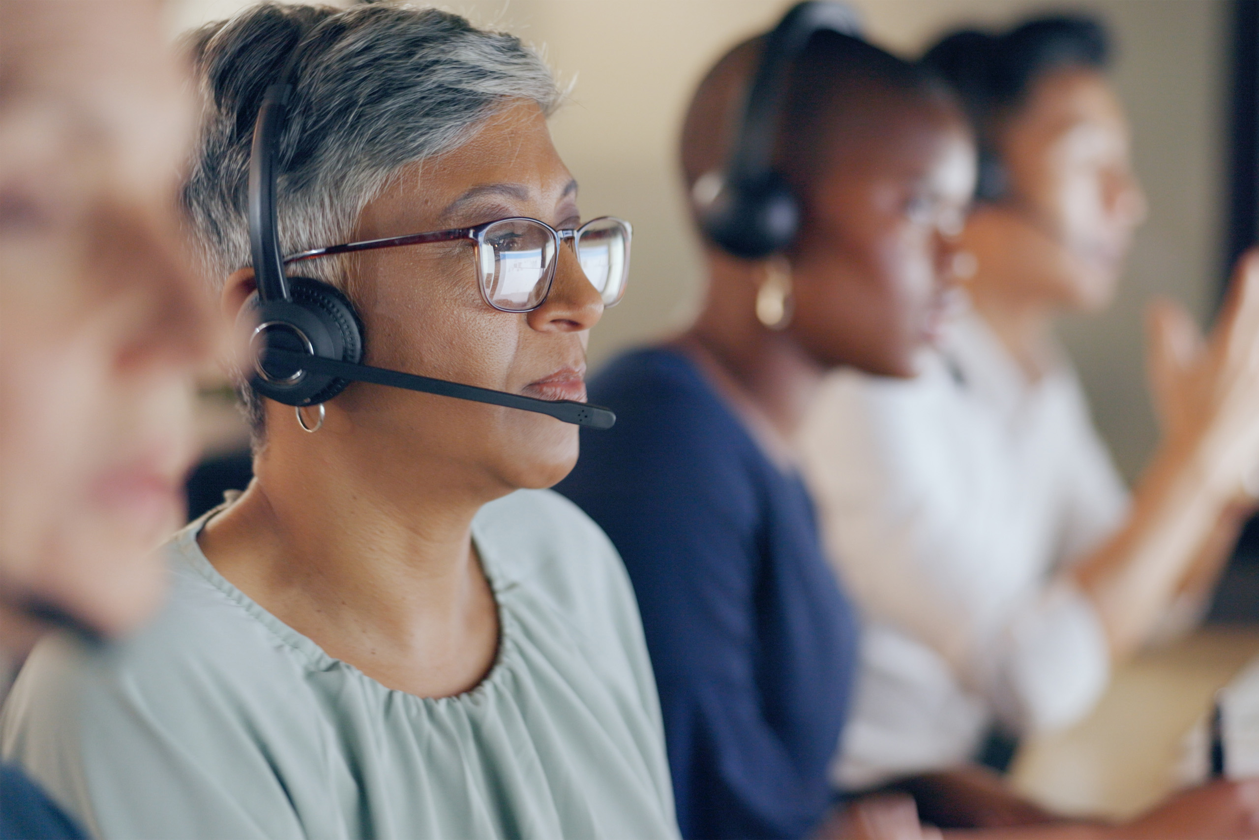 Four people, wearing headsets, answering calls at computer desks