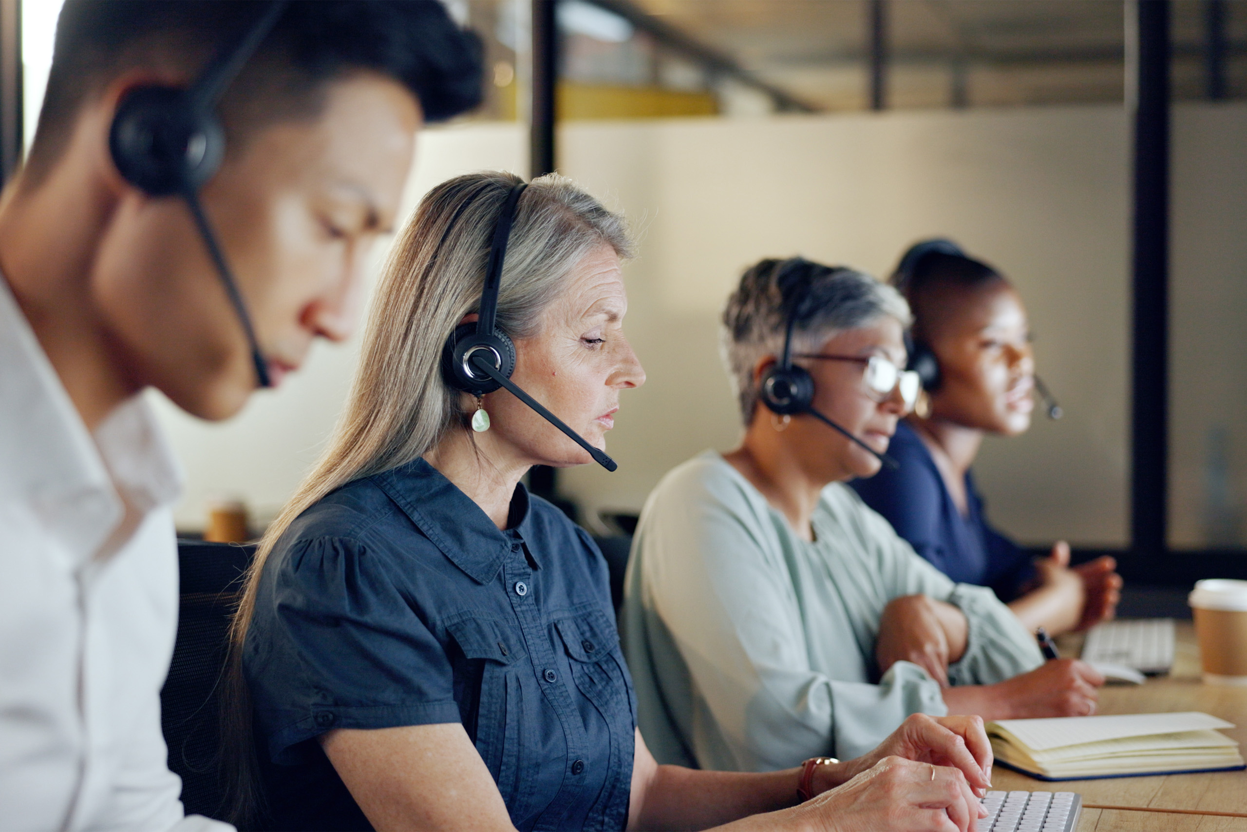 Four people with headsets in an office answering calls