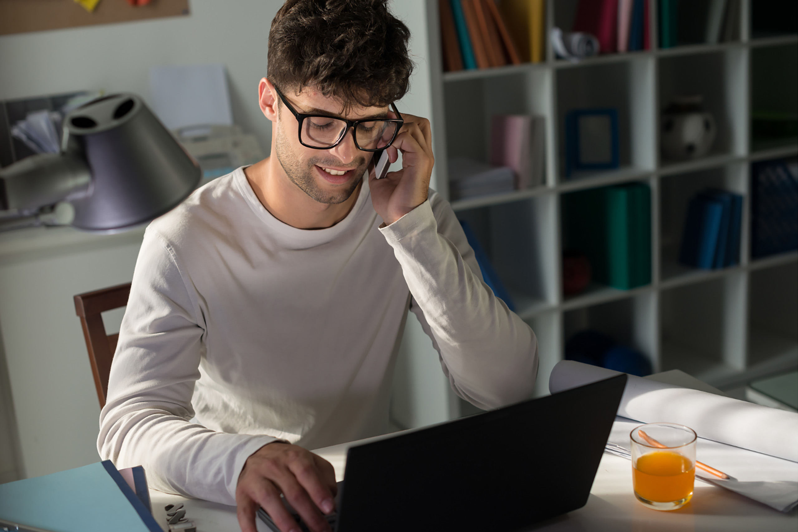 Young man with dark hair and glasses talking on the phone