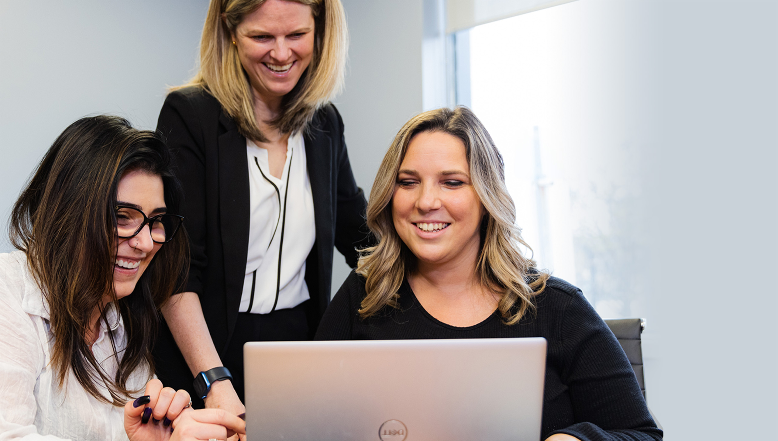 Elisha, Dana. and Jennifer collaborating on a silver laptop