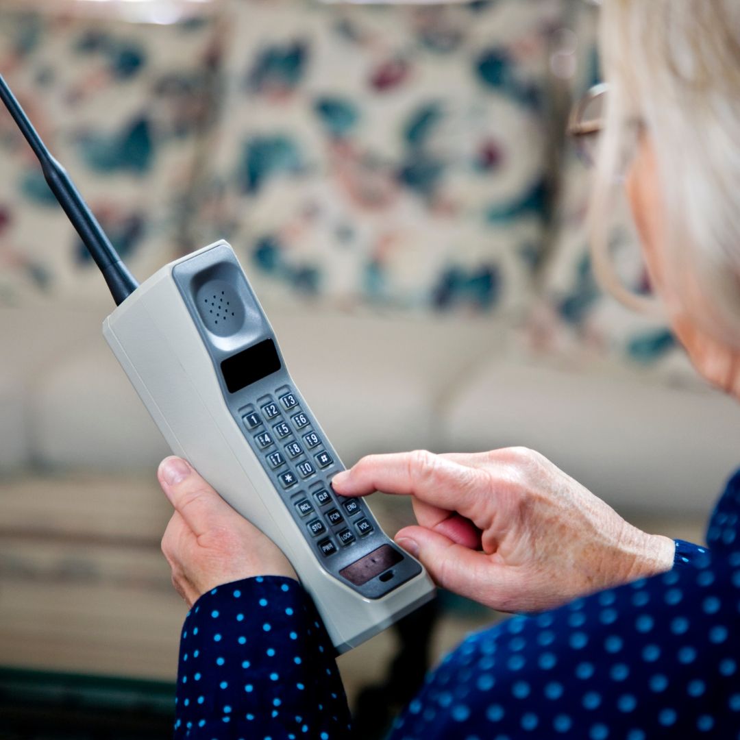 Woman dialling a number on a vintage brick telephone